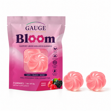 A pink stand-up pouch of Gauge Bloom dietary supplement gummies with two loose pink gummies placed in front on a white background.